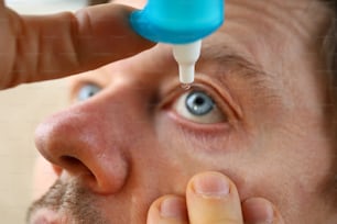 Mão masculina colocando gotas de líquido em seu olho resolvendo o problema de visão closeup
