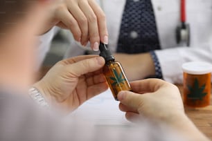 病気の患者に大麻油の入ったペットボトルを与える医師のクローズアップビュー。代替療法または投薬。民間療法とヘルスケアの概念