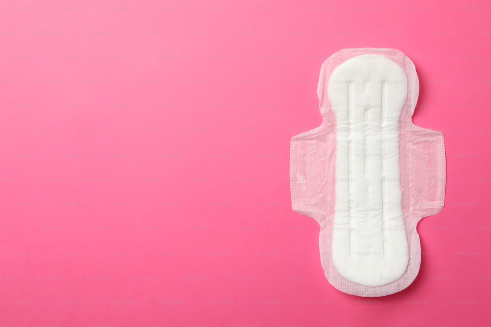 Sanitary pad on pink background, top view