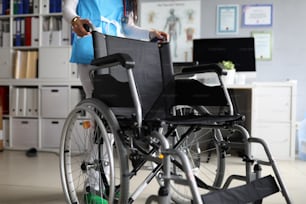Close-up of modern wheelchair equipment for disabled people. Hospital room with all necessary tools and instruments. Nurse in working uniform. Medicine concept