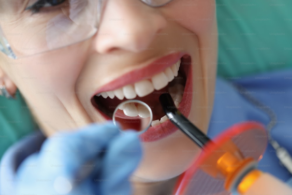 Ritratto di una cliente femminile su appuntamento nell'armadio di stomatologia che riceve la procedura di sbiancamento e il controllo completo. Il dentista si occupa della cura dei denti. Concetto di salute