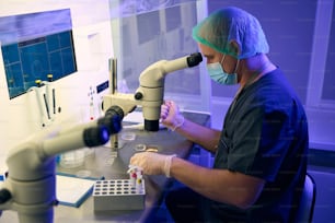 Embriologista estudando sangue do cordão umbilical sob microscópio, retirando células-tronco para posterior congelamento e armazenamento em laboratório especial