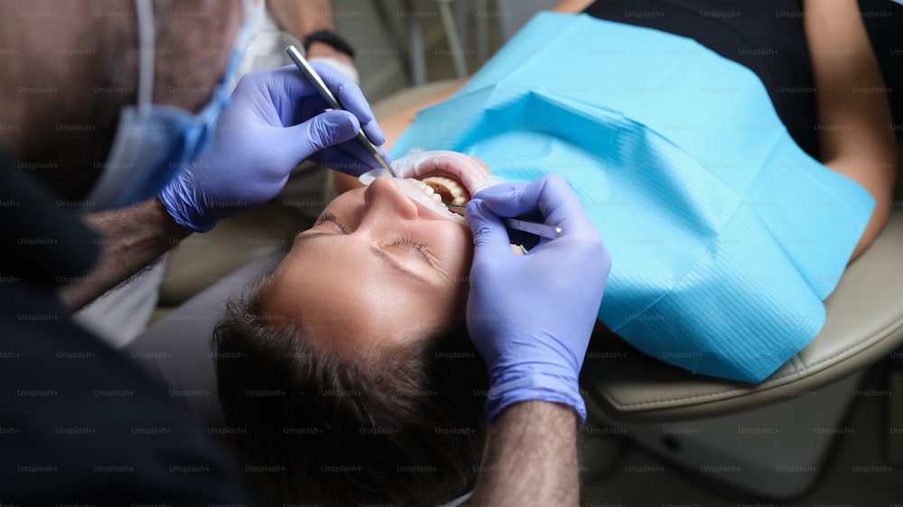 치과 의사가 치과에서 여성 환자에게 충치가 있는 치아를 치료합니다. 치아 개념의 관리 및 치료