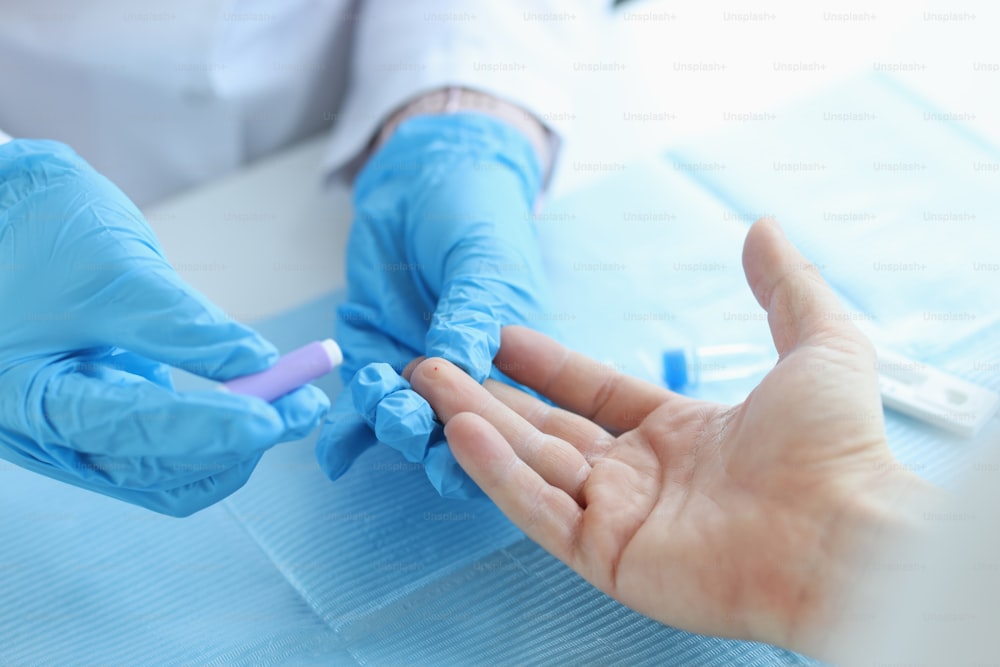 Gloved doctor takes blood test with lancet from patient at clinic. Delivery of analyzes concept