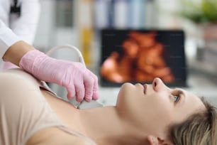 Doctor's hands on a woman's neck, ultrasound of the thyroid gland, close-up. Diagnosis of thyroiditis, treatment of hypothyroidism