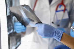 Close-up of female doctor holding x ray results. Qualified medical worker analyzing scan. Protective uniform. Healthcare and checkup. Medicine and prescription concept