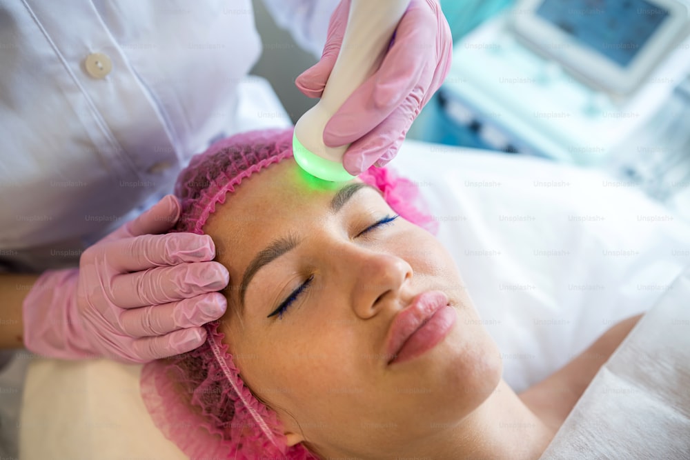 Una ragazza ad un appuntamento con un'estetista sta facendo una pulizia del viso ad ultrasuoni. La pulizia ad ultrasuoni è la pulizia dell'hardware che viene eseguita con l'aiuto di onde ultrasoniche ad alta frequenza.