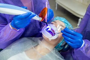 el dentista con su ayudante en mono utiliza lámparas UV y luego trata los dientes de los pacientes. Concepto de restauración dental