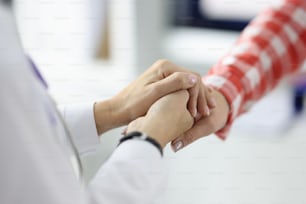 白衣を着た医師がクリニックの接写で患者と握手。成功する治療コンセプト