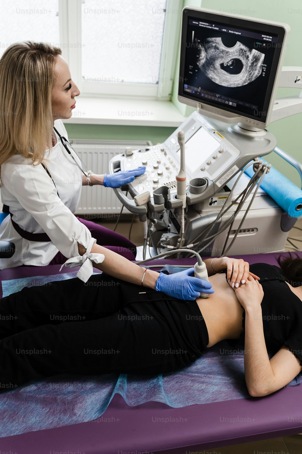 Pregnancy and maternity. Gynecologist conducts ultrasound scan for pregnant young woman on early pregnancy period and look on the screen in hospital