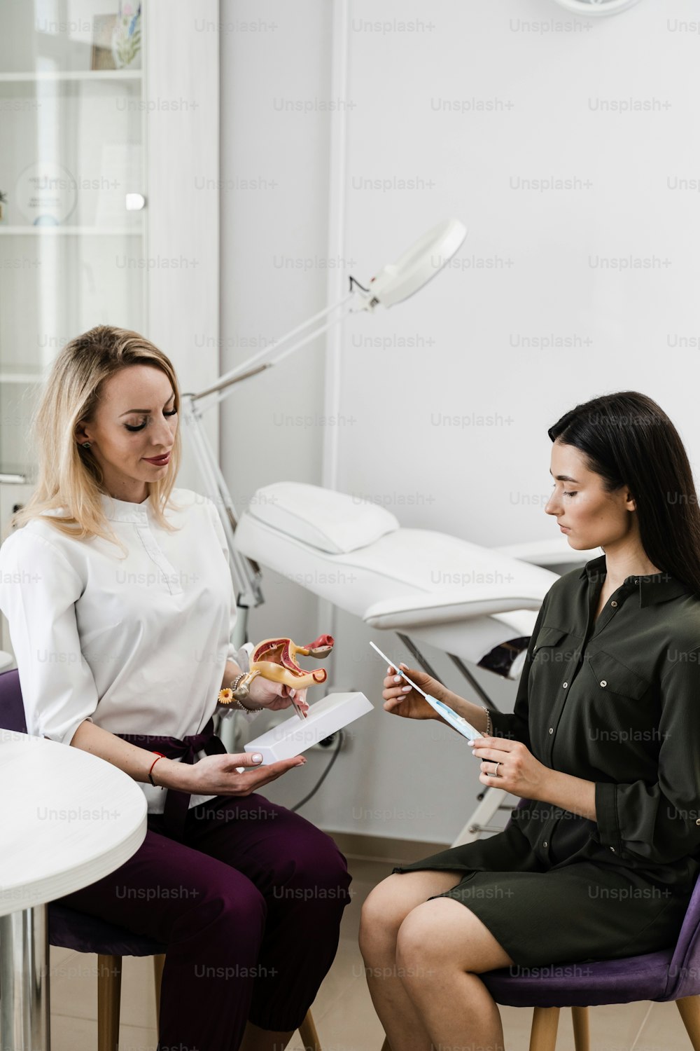 Girl is holding IUD intrauterine device and listen gynecologist about process installing in uterus. Gynecology consultation