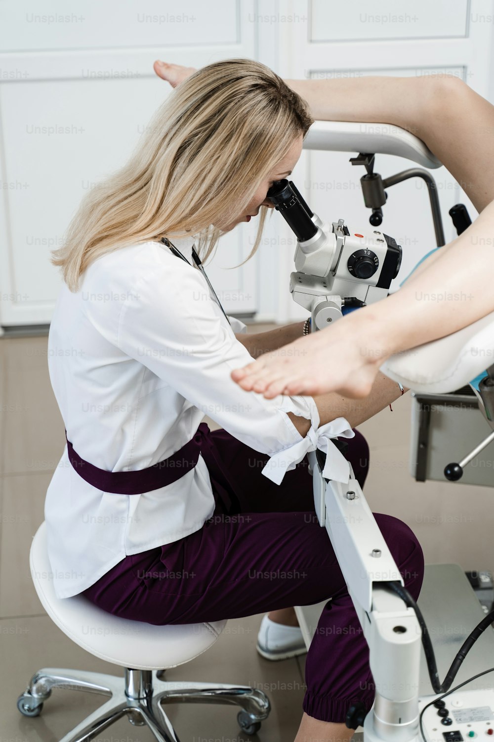 Gynecologist is looking in colposcope for detail examination of disease. Gynecologist does colposcopy procedure to closely examine cervix, vagina and vulva of girl in gynecology clinic