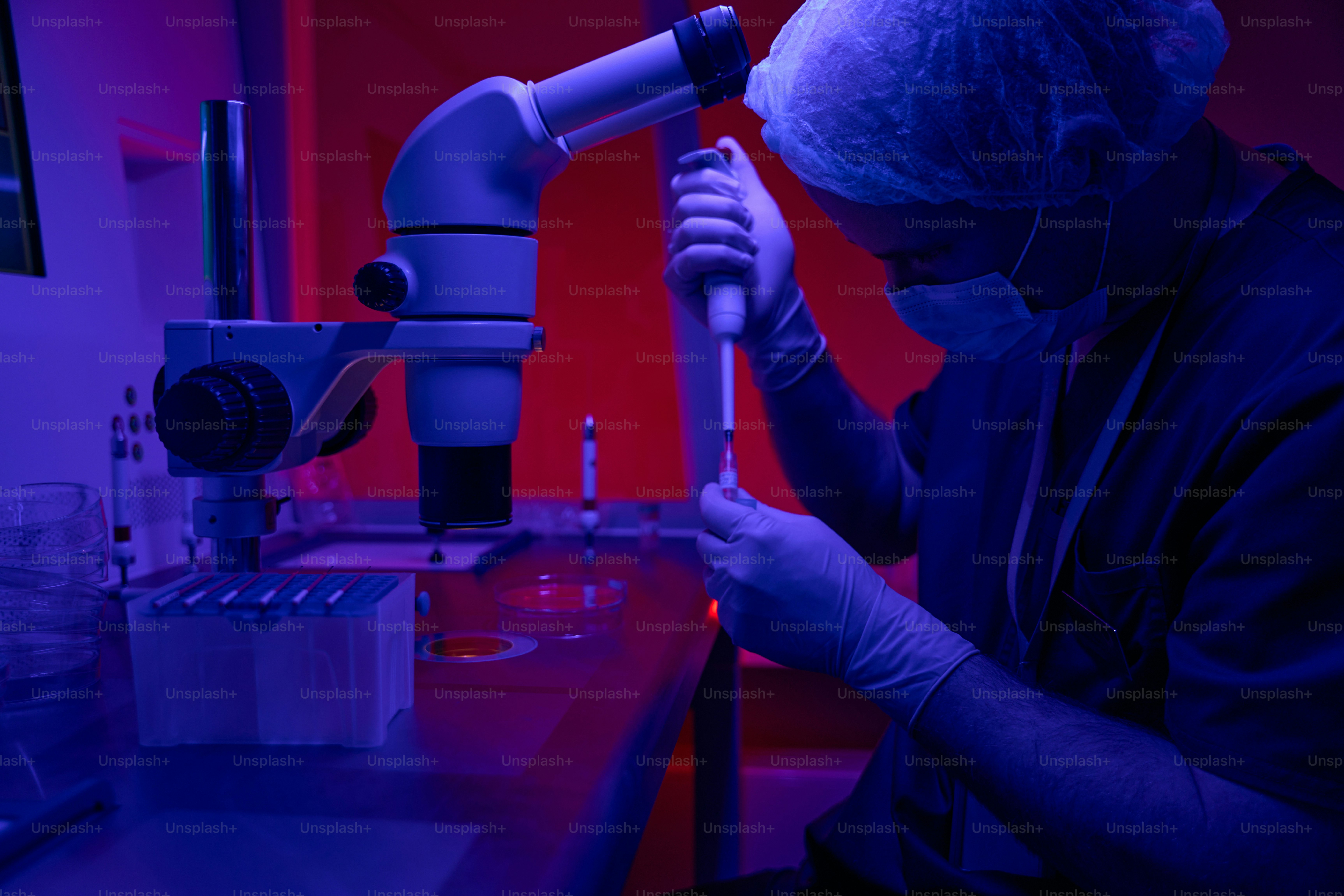 Genetischer Laborforscher entnimmt Proben aus dem Reagenzglas, um sie unter dem Mikroskop zu untersuchen und verschiedene Anomalien und Mutationen auszuschließen
