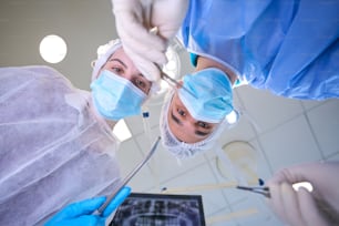 Un cirujano masculino sostiene una aguja quirúrgica especial en sus manos, una asistente femenina está cerca