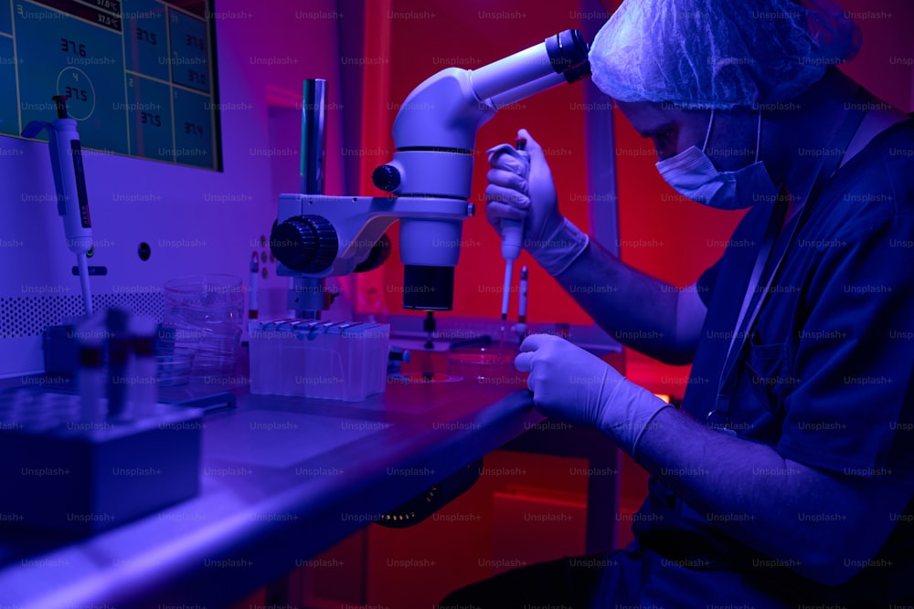 Scienziato di biolaboratorio che conduce un test di immunoassorbimento enzimatico, prelevando campioni di sangue da provette