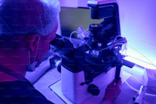 Tecnico di laboratorio dell'uomo che regola il microscopio con il micromanipolatore prima di lavorare con cellule staminali o embrioni