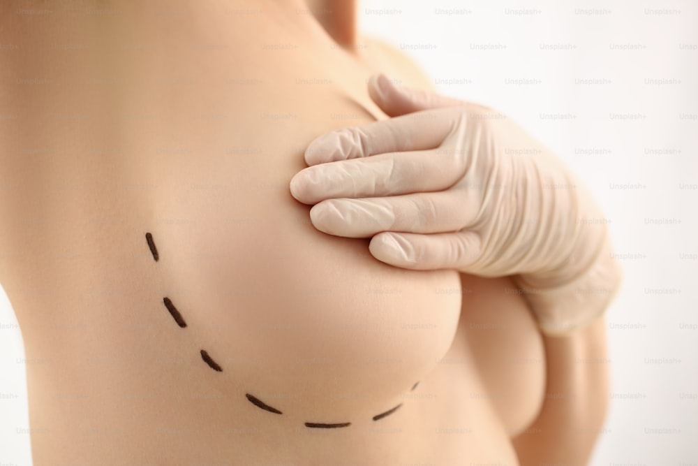 医師の乳房クリニックのレセプションで胸のクローズアップを保持する手袋の女性の手。乳腺テスト生検インプラントシリコンインサート腫瘍人間概念