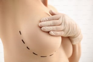 Main féminine dans des gants tenant un gros plan sur la poitrine à la réception de la clinique de mammologie du médecin. Glandes mammaires test biopsie implant silicone insert tumeur concept humain