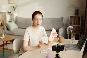 Portrait of young woman holding two types of pads to camera and filming educational video on feminine products