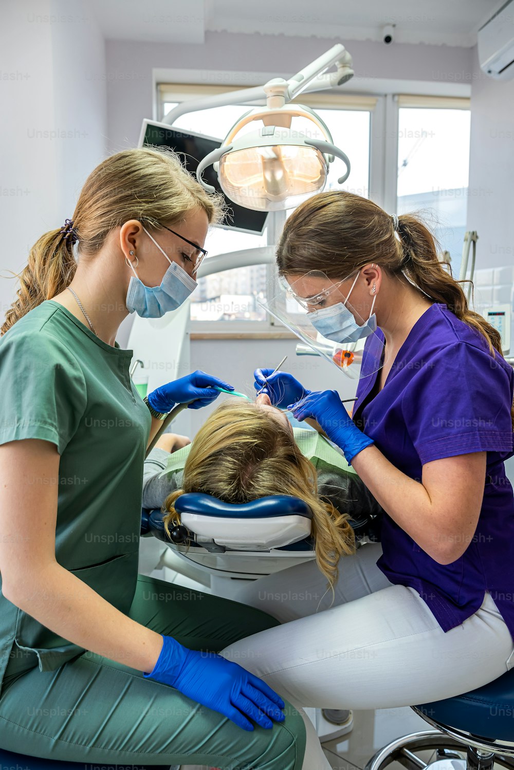 Dentistes avec miroir, perceuse et pistolet à eau à air comprimé dentaire traitant les dents des patients adultes à la clinique dentaire