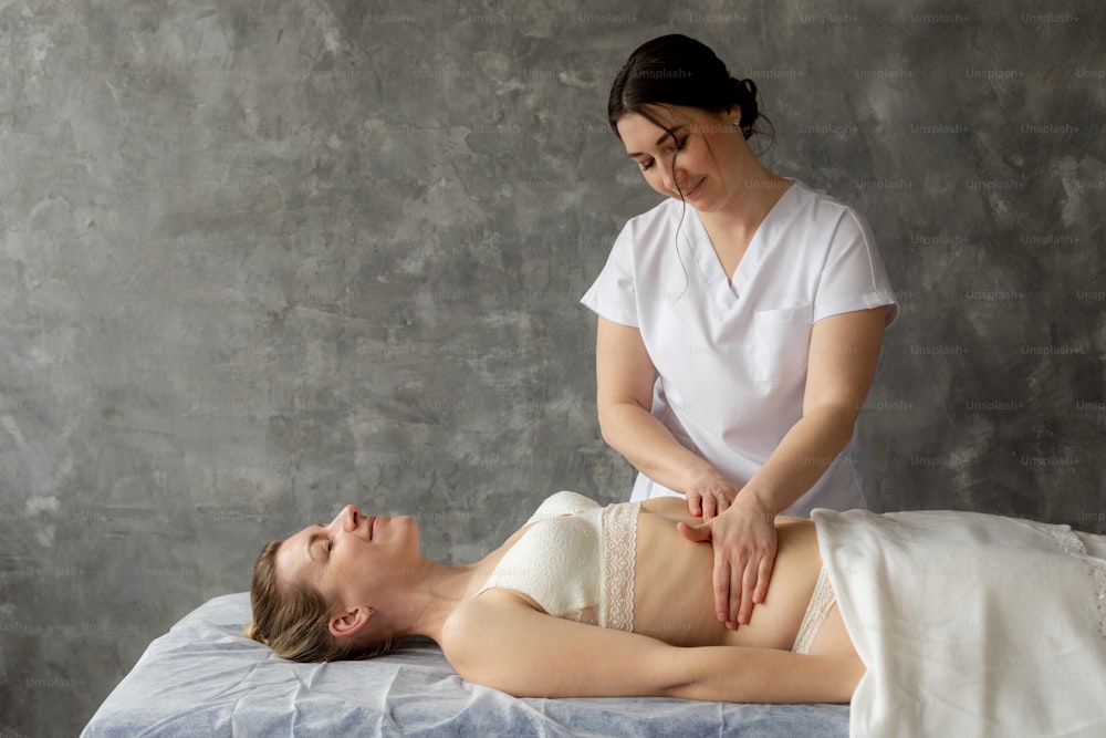 Smiling female doctor physiotherapist, osteopath fixing patient chest to cure spasm and pain. Manual therapy salon or clinic. Body palpation, professional treatment, alternative medicine. Copy space