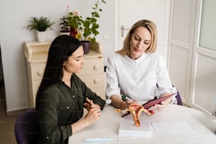 Consultation with gynecologist and discussion of reproductive health of woman in gynecology clinic. Gynecologist asks young girl about menstrual cycle and writes down information in the questionnaire