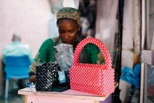 a woman sitting at a table with a red and white purse