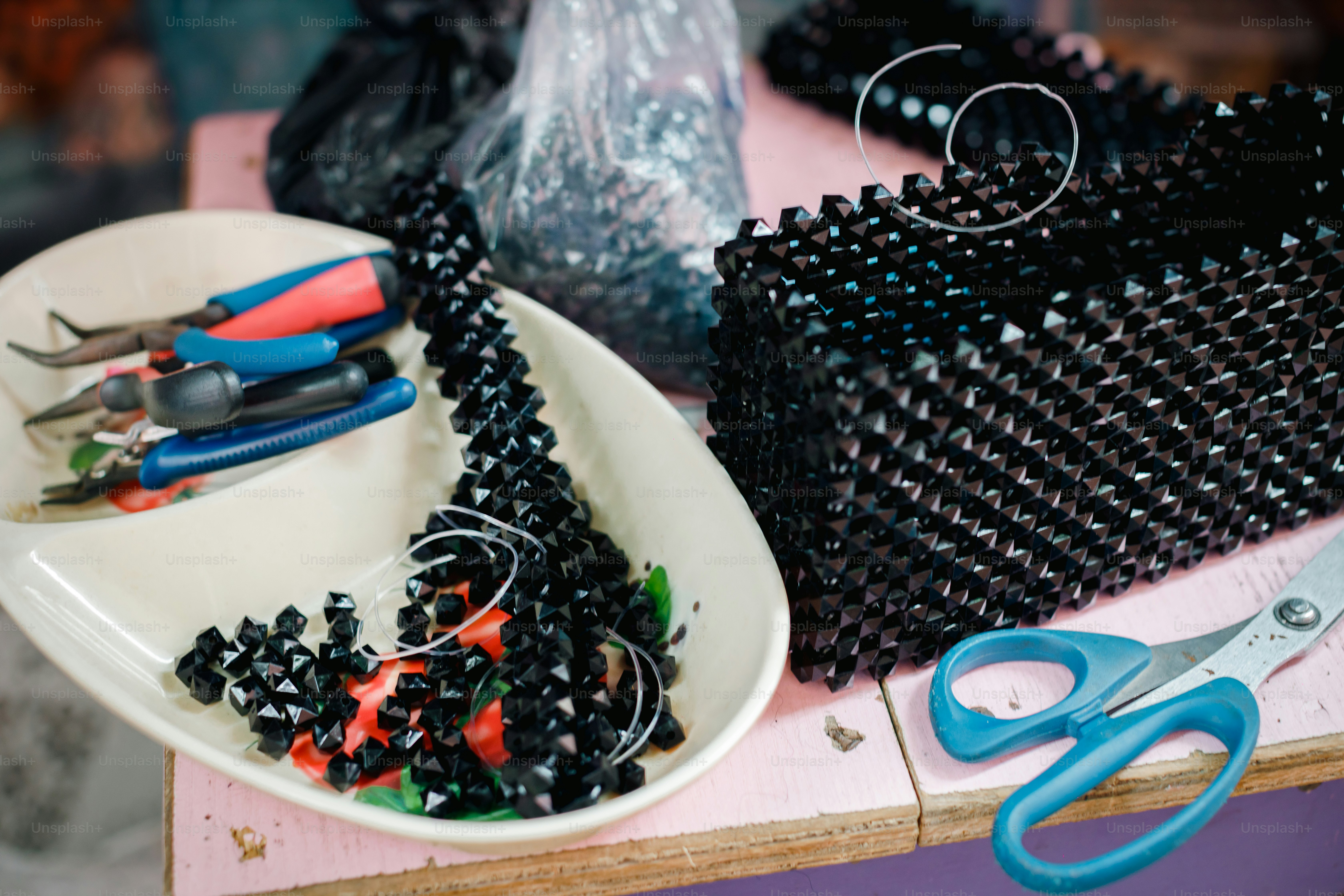 a white plate topped with black beads next to a pair of scissors