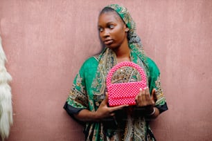 a woman holding a pink purse in front of a pink wall