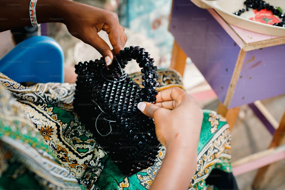 a woman is holding a black beaded purse