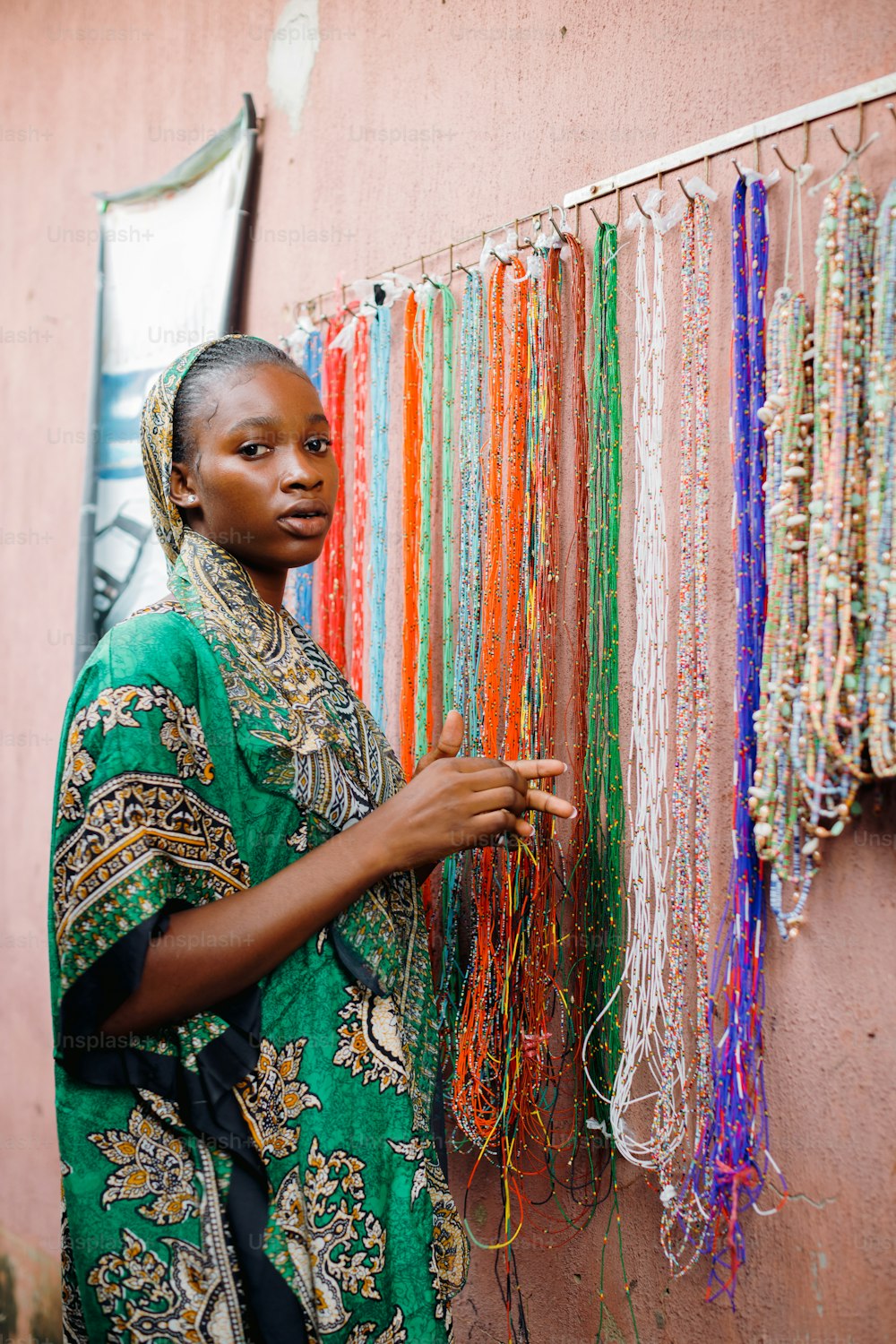 a woman standing next to a wall covered in beads