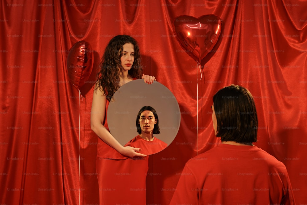 a woman in a red dress looking at a mirror