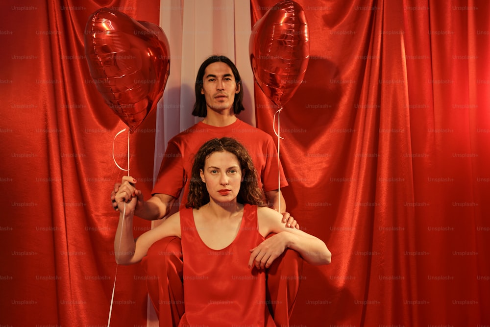 a man and a woman standing in front of red balloons