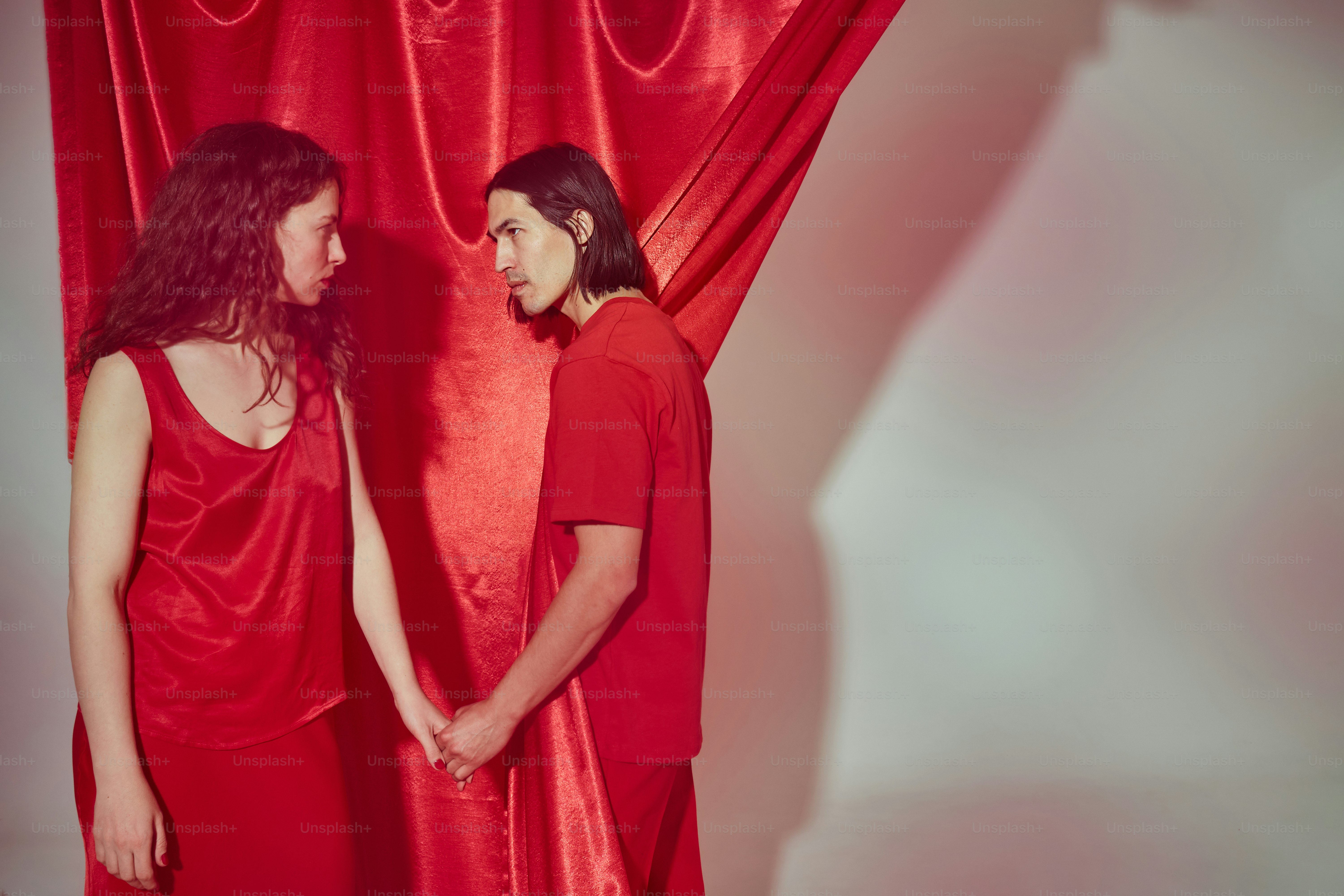 a man and a woman standing in front of a red curtain