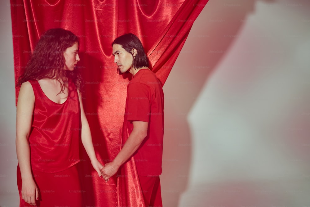 a man and a woman standing in front of a red curtain