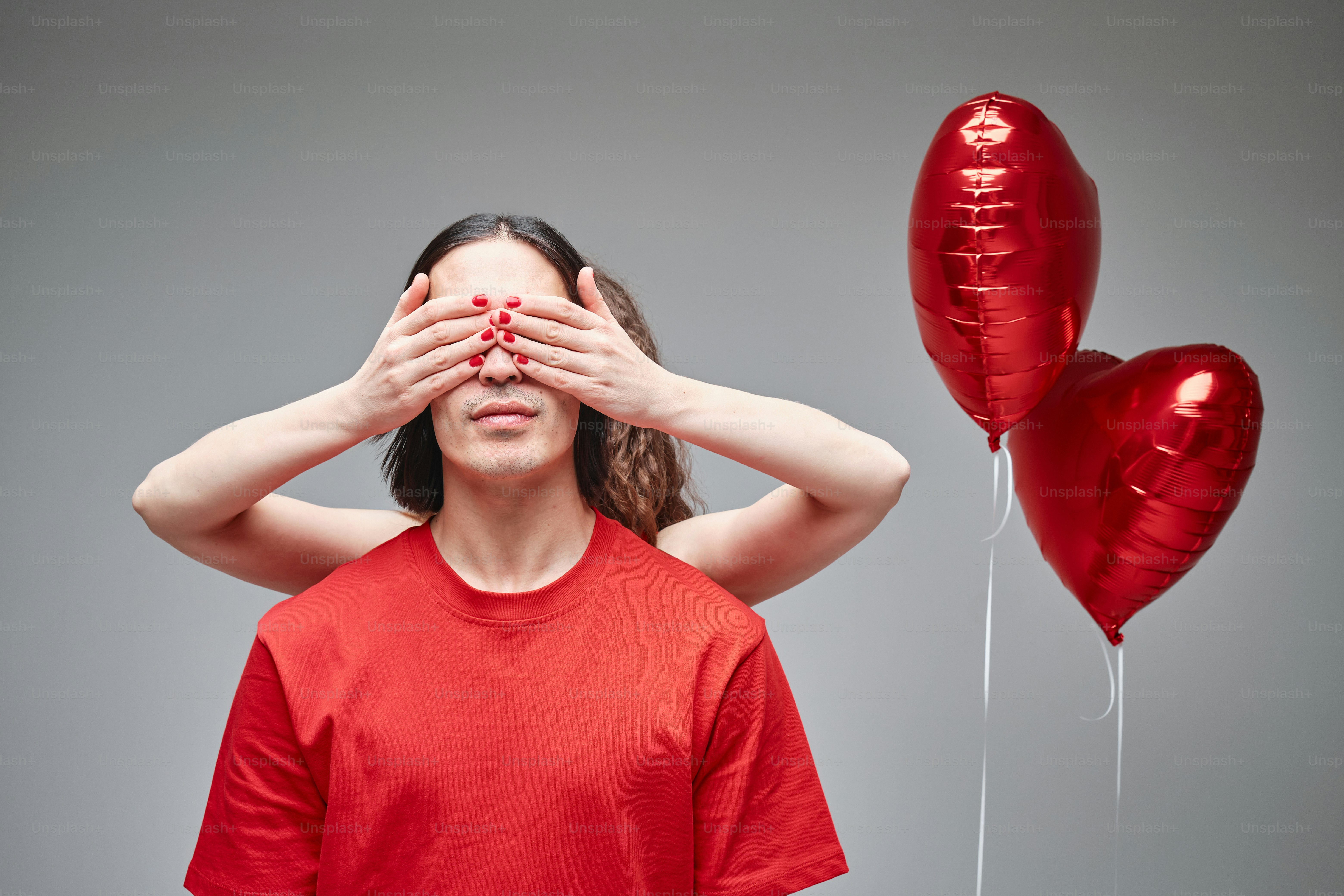 Un hombre tapándose los ojos junto a globos