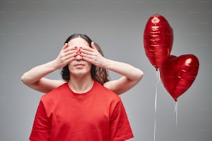 a man covering his eyes next to balloons