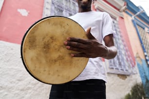 a man holding a large drum in front of a building