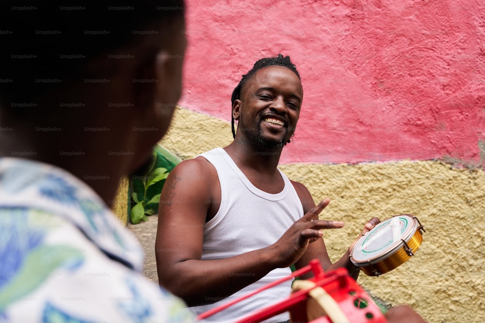 un homme jouant d’un instrument de musique devant un mur rose et jaune