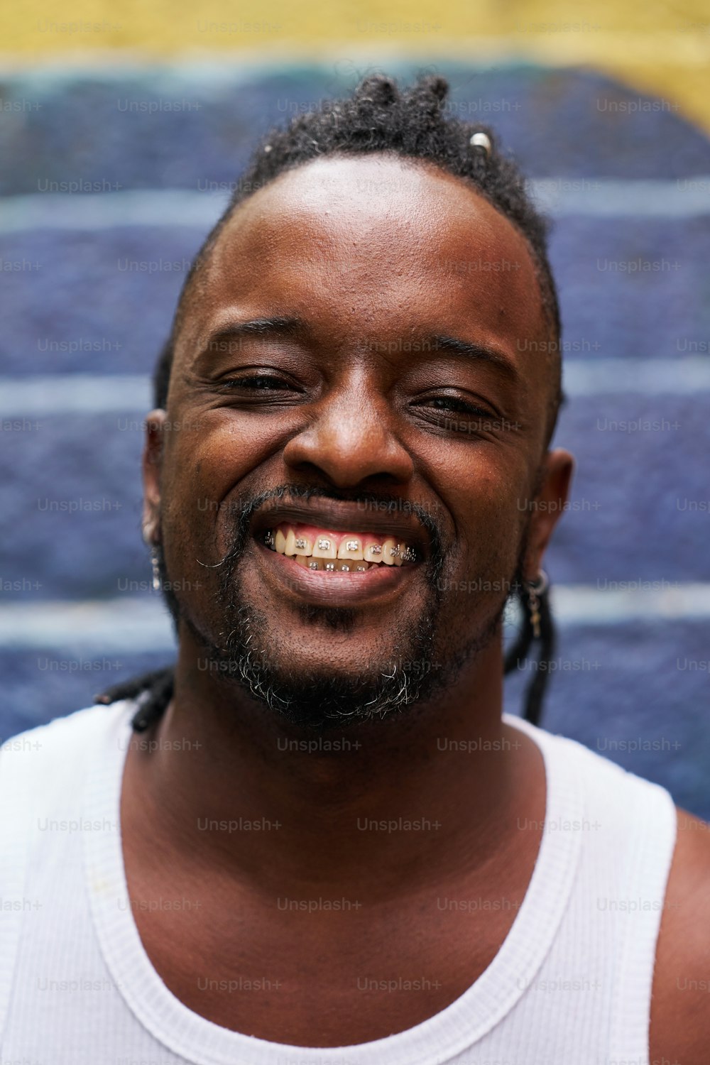 a man with dreadlocks smiles at the camera