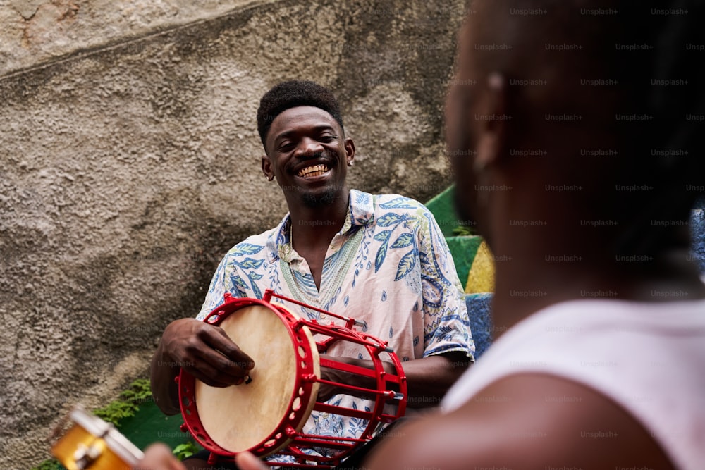 a man holding a drum and smiling at another man