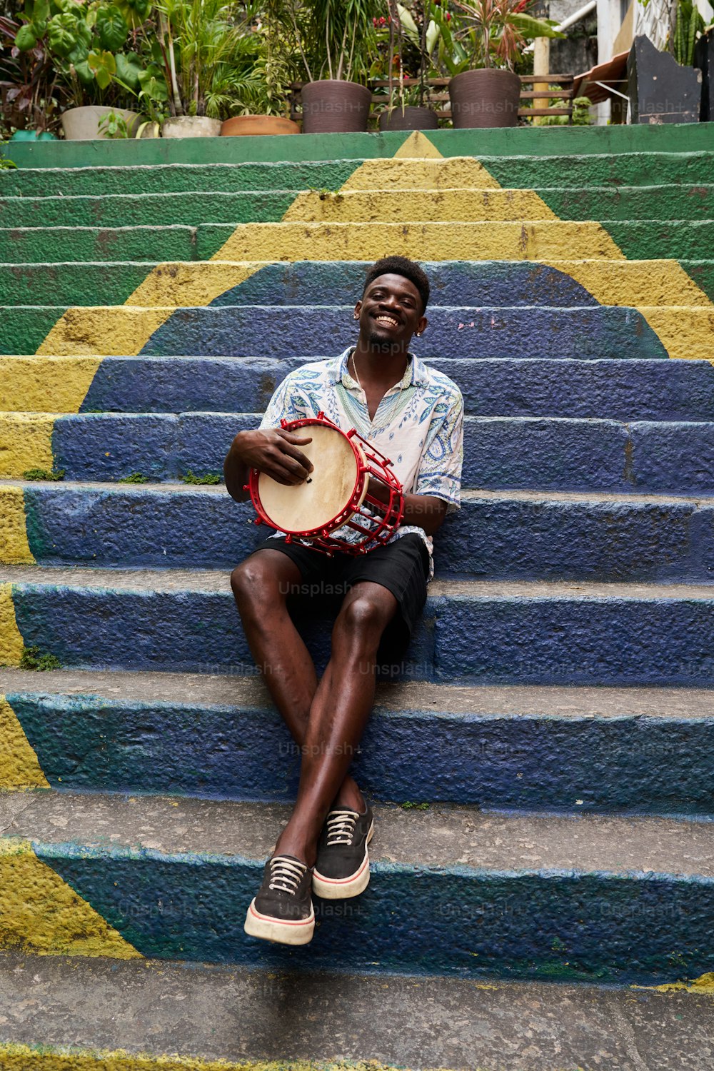 a man sitting on a set of steps holding a drum