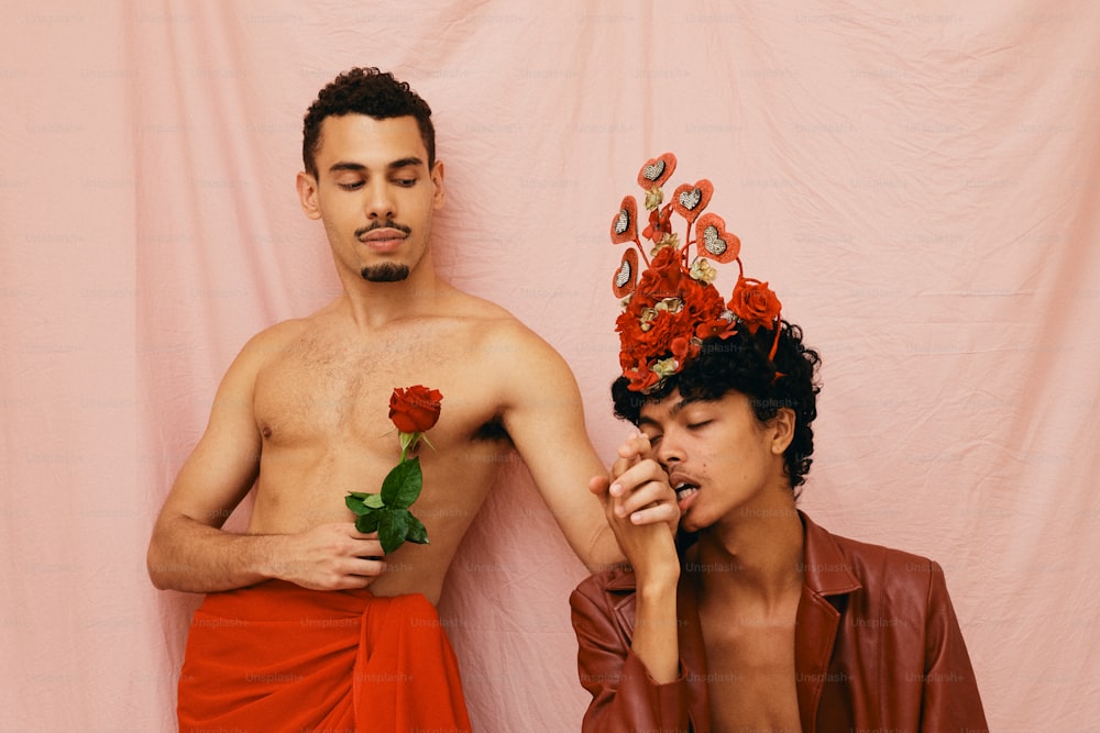 un uomo con una corona di fiori in testa accanto a un uomo con una rosa