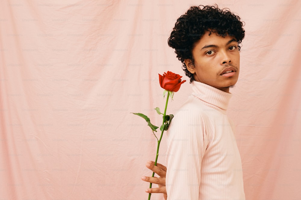 a young man holding a single red rose