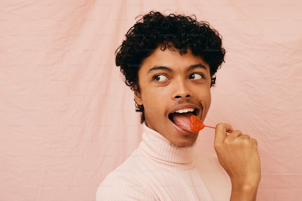 a man with curly hair is holding a carrot in his mouth