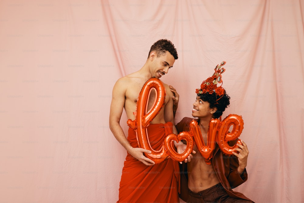 a man and a woman holding balloons in the shape of the word love