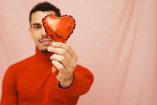 a man holding a heart shaped balloon in his hand