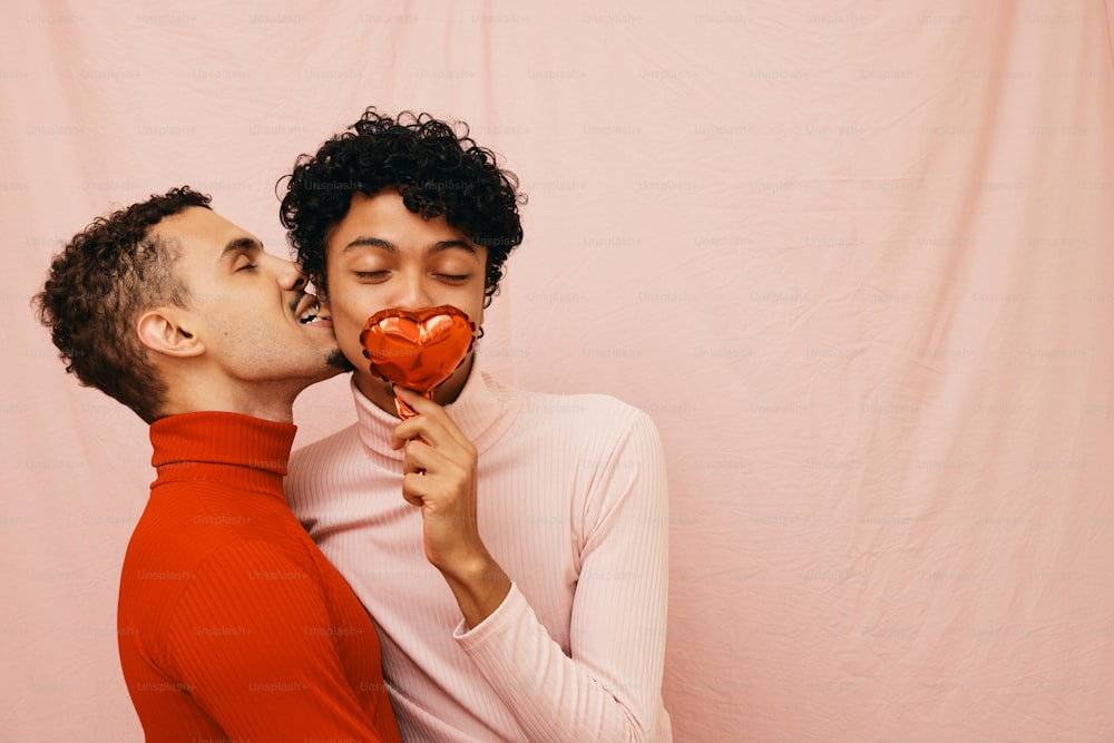 un hombre y una mujer besándose mientras sostienen un corazón