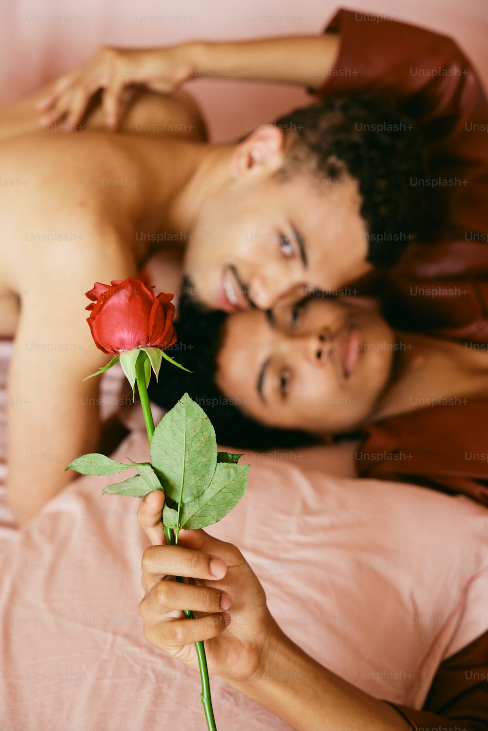 a man laying in bed next to a woman holding a rose