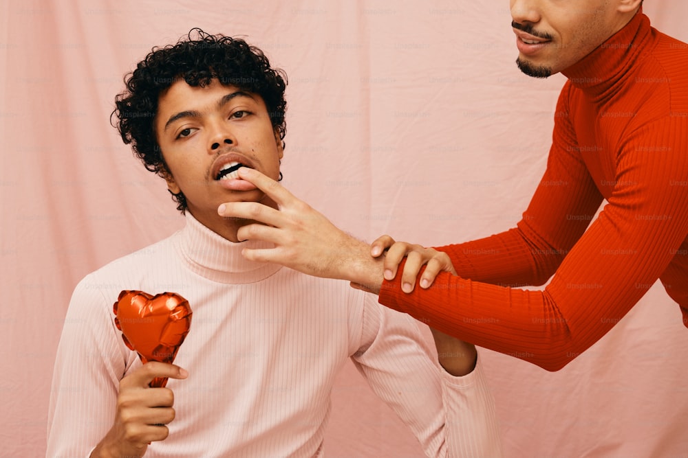 a man holding a heart shaped chocolate in front of another man